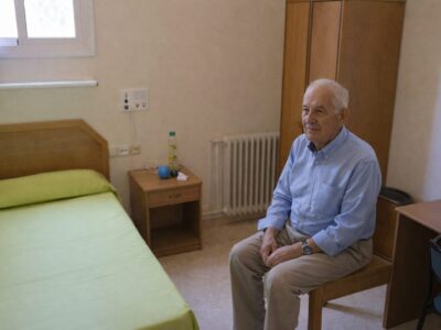 Persona mayor con Alzheimer en habitación individual luminosa y acogedora