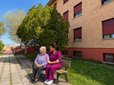 Gerocultora acompañando a una residente en el jardín de una residencia de mayores